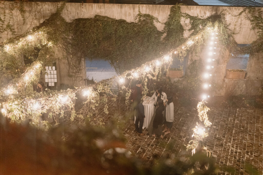 wedding guests gathering around to celebrate this wedding with gorgeous twinkle lights above the brick walls