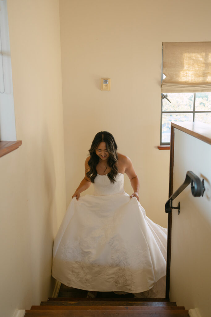 bride walking up staircase and holding her wedding gown