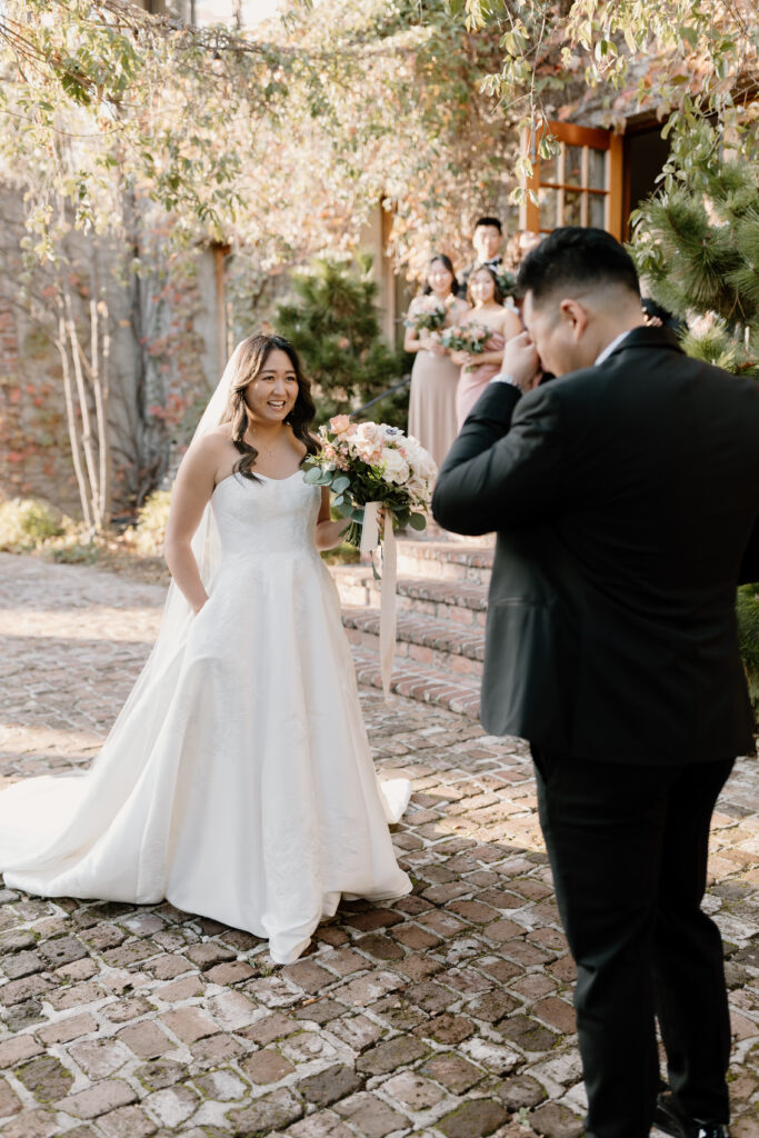 groom wiping tears from eyes after looking at bride for first time during first look wedding photos