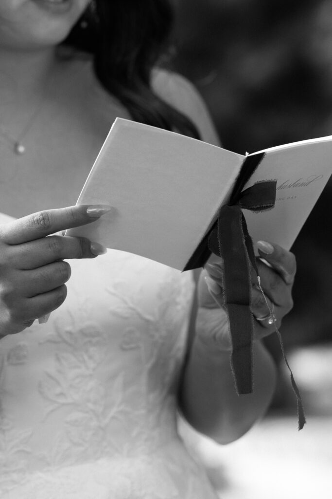 bride holding her vow book while saying vows during wedding ceremony