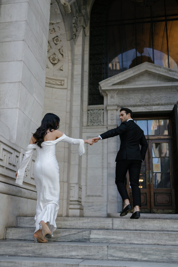 man and woman walking up stairs in front of library for engagement photos